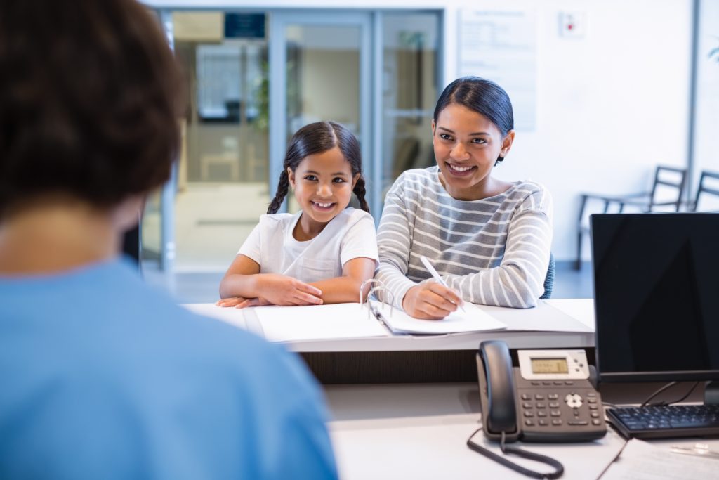 Mother and daughter filling out paperwork at counter